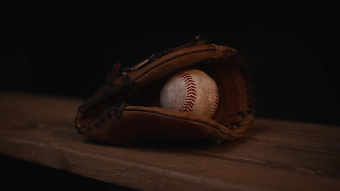 Guante de béisbol con una pelota sobre una banca de madera